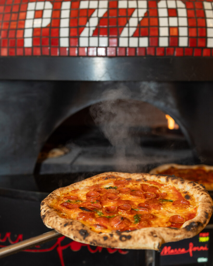 Freshly baked pizza coming out of the oven at Pizza Gemelle Nantucket